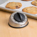 A Taylor stainless steel kitchen timer next to a tray of cookies with a cookie on it.