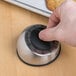 A hand turning the dial on a Taylor stainless steel kitchen timer.