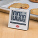 A Cooper-Atkins digital kitchen timer on a counter next to cookies.