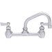 A stainless steel Fisher wall mount faucet with two lever handles and a swing nozzle.