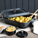 A gray enamel coated roasting pan with a lid and food inside on a table.