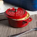 A red and white enamel coated cast aluminum GET bistro pot with a lid.