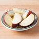 A Tuxton Green Bay china monkey dish filled with sliced apples.