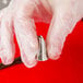 A person in white gloves using an Ateco Lily-of-the-Valley piping tip to pipe frosting.