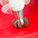 A person using an Ateco Russian ball tip piping tip to pipe chocolate.