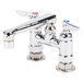 A chrome T&amp;S deck-mounted faucet with two lever handles and a swivel nozzle.