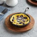 A Valor pre-seasoned mini cast iron skillet filled with an omelette and blueberries on a wooden plate.