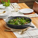 A Valor Pre-Seasoned Cast Iron Skillet filled with cooked greens on a table.