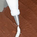 A close-up of an Ateco plain piping tip on a pastry bag with white frosting.