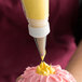 A person using an Ateco plain piping tip to decorate a cupcake.