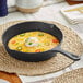 A Valor pre-seasoned cast iron skillet with eggs, cheese, and jalapeno peppers cooking in it.
