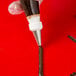A hand using an Ateco plain piping tip to inject brown liquid into a piece of chocolate.