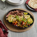 A Valor pre-seasoned cast iron fajita skillet with steak and vegetables on a table.