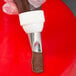 A hand using an Ateco curved petal piping tip to pipe chocolate on a cake.