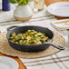 A Valor pre-seasoned cast iron skillet with brussels sprouts on a table.