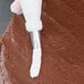 A person using an Ateco ruffle piping tip to frost a cake.
