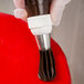 A hand using an Ateco closed star piping tip on a red cake.