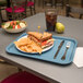 A Carlisle slate blue plastic fast food tray with a sandwich, chips, and a drink on it.