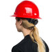A woman wearing a Cordova red hard hat with a ponytail.