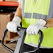 A man wearing Cordova cowhide leather driver's gloves and a safety vest holding a hand truck.