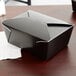 A black Fold-Pak Bio-Pak take-out box with a lid on a table.