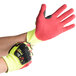 A person wearing yellow and red Cordova OGRE-CR+ heavy duty work gloves.