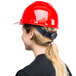 A woman wearing a red Cordova Duo hard hat with a ponytail.