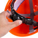 A person holding a Cordova safety helmet with a ratchet suspension strap.