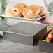 A Tablecraft stainless steel rectangular bowl holding bagels on a counter.