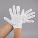 A person's hands wearing white Cordova inspection gloves.