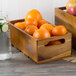 A Tablecraft Gastronorm acacia wood crate filled with oranges.