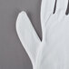 A Cordova white fabric inspection glove on a gray surface.