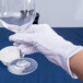 A hand wearing white Cordova Inspector's gloves holding a glass.