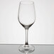 An empty Arcoroc wine glass on a reflective surface.