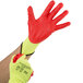 A person wearing yellow Cordova heavy duty work gloves with red wrist and palm coating.