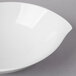 A Villeroy & Boch white porcelain bowl with a curved edge on a gray surface.