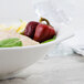 A Villeroy & Boch white porcelain bowl filled with chicken and peppers on a marble surface.