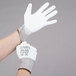 A person wearing Cordova white gloves with white background.