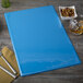 A blue Menu Solutions folder on a table with a menu inside.