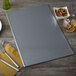 A gray rectangular Menu Solutions Hamilton silver menu board on a table with silverware and a plate.