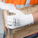 A person wearing Cordova white gloves with white palm coating holding a wooden box.