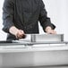 A person holding a stainless steel Choice steam table spillage pan.