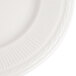 A close-up of a 10 1/4" ivory china plate with an embossed rim.