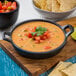 A Valor pre-seasoned mini cast iron round casserole dish filled with soup and tortilla chips on a table.