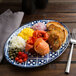 An Arcoroc Candour Azure oval platter with food on a table.