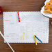 A Hoffmaster kids placemat with crayons and a plate of food on a table.
