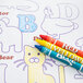 A group of colored crayons on a Hoffmaster Kids Color Me Design Placemat.