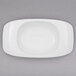 A white rectangular plate with a rounded center and a bowl on top.