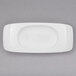 A white rectangular plate with a small oval bowl on top.