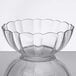 An Arcoroc clear glass bowl with a scalloped edge on a table.